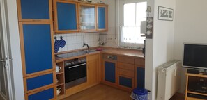 Eine kleine Küche mit Holzausstattung, einem Backofen, einer Spüle und einem Fenster.