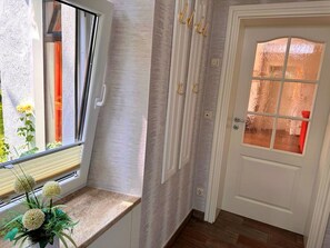 Ein Zimmer mit Fenster, einer Tür mit Milchglas und einer Pflanze auf der Fensterbank.