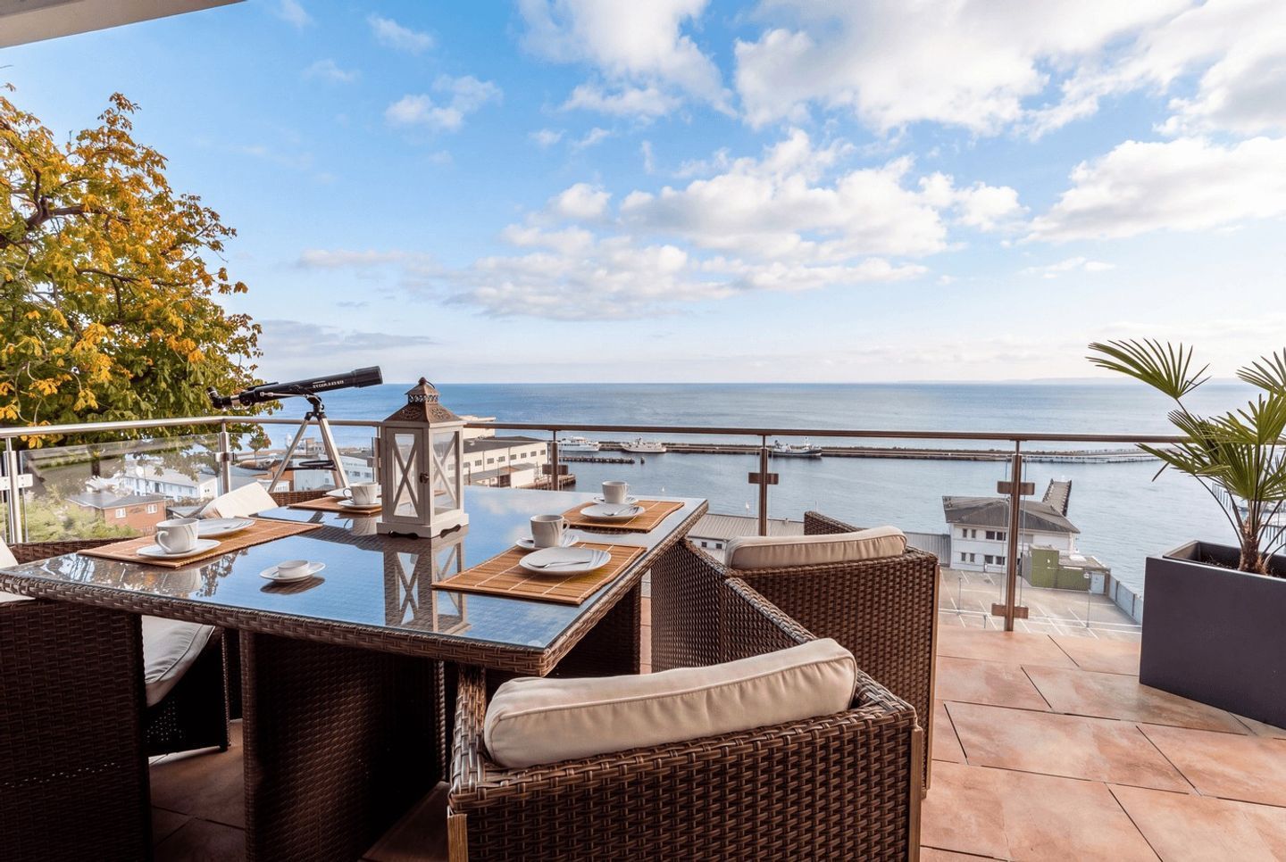 A terrace with wicker furniture, a telescope, and a view of the sea.