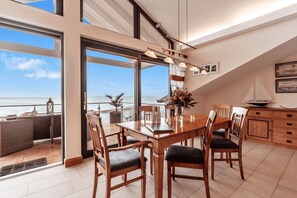 A dining area with a view of the sea, a table with chairs, and a ship model on the wall. - Villa Friede-Marie - Penthouse Sophie - Villa Friede-Marie, Penthouse Sophie - (Sassnitz auf Rügen)