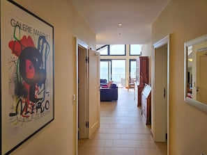 Ein Flur mit einem großen abstrakten Gemälde, einer Couch und einem Essbereich mit Blick.