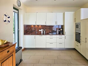 Eine moderne Küche mit weißen Schränken, einer Granitarbeitsplatte, einer Edelstahlspüle und einem eingebauten Backofen.