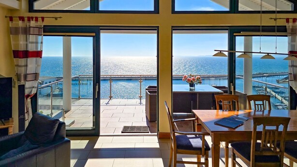 Una habitación con ventanas amplias, un comedor y vista al mar.