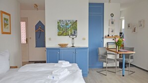 A hotel room with a bed, a desk, a chair, a blue wardrobe, and a painting on the wall. - Apartment with Ocean View and 2 Balconies, Villa Monika, Apt. 7 - Villa Monika, Apt. 7 (Sassnitz auf Rügen)