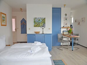 A hotel room with a bed, a desk, a chair, a blue wardrobe, and a painting on the wall. - Apartment with Ocean View and 2 Balconies, Villa Monika, Apt. 7 - Villa Monika, Apt. 7 (Sassnitz auf Rügen)