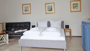 A bedroom with a bed, a black leather sofa, a small table, and framed pictures on the wall. - Apartment with Ocean View and 2 Balconies, Villa Monika, Apt. 7 - Villa Monika, Apt. 7 (Sassnitz auf Rügen)