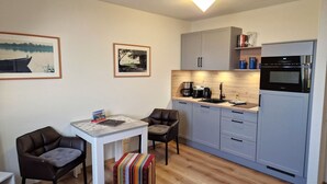 Una cucina compatta con zona pranzo, macchina del caffè e frigorifero.