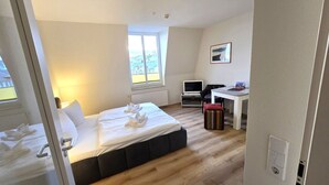 Una camera d'albergo con un letto, una scrivania, un computer e una finestra.