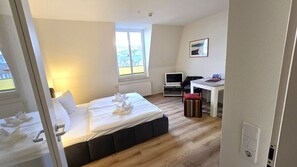 Ein Hotelzimmer mit Bett, Schreibtisch, Computer und Fenster.