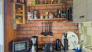 Een keuken met een bakstenen muur, een koffiezetapparaat, een broodrooster en diverse keukengerei.