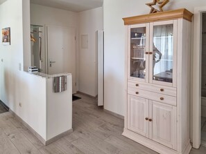 Eine Küche mit einem eingebauten Kühlschrank, einem Holzkabinett mit Glastüren und einem Holzboden.