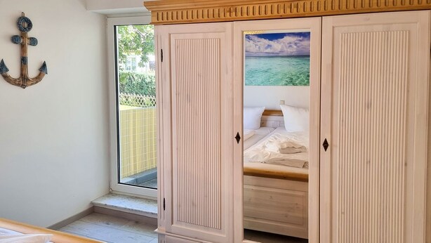Ein Schlafzimmer mit Bett, Kleiderschrank und einem Fenster mit Meerblick.