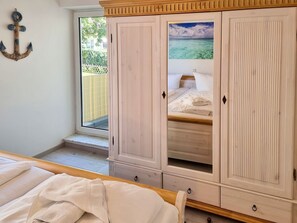 Une chambre à coucher avec un lit, une armoire et une fenêtre donnant sur la mer.