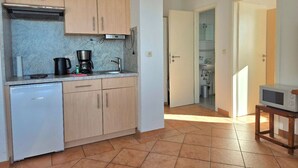 Una cucina compatta con lavastoviglie, macchina del caffè e forno a microonde su un tavolino.
