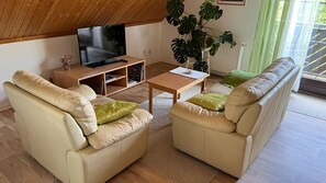 A living room with a television, two sofas, a coffee table, and a large plant. - Stockrose vacation apartment - very close to the Jasmund National Park (Lohme OT Nipmerow)