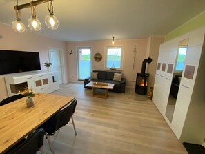 A modern living room with a TV, sofa, coffee table, and a fireplace. - Vacation apartment Tiny - on the edge of the national park in Hagen - Ferienwohnung Tiny - (Lohme OT Hagen)