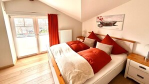 Una camera da letto con un letto, un comodino, una finestra con tende, un termosifone e un quadro appeso al muro.