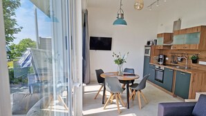 Moderni keittiö, jossa on ruokailutila, sohva ja näkymä lasiovesta.