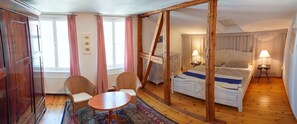 A room with a bed, two chairs, a small table, and a window with curtains. - Jasmundhus on Rügen - Holiday apartment Backbord (Neddesitz auf Rügen)