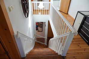 A wooden staircase with white railings leading to a second-floor landing. - Jasmundhus on Rügen - Holiday apartment Backbord (Neddesitz auf Rügen)