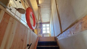 Una escalera de madera con un flotador en la pared, una ventana en la parte superior y una barandilla metálica.