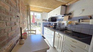 Una cocina compacta con armarios blancos, una encimera negra y un ventanal visible.
