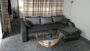 Una sala de estar con un sofá, una mesa de centro y una cortina.