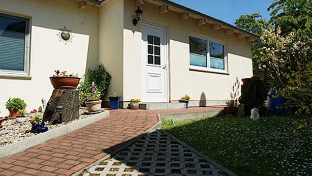 Una casa con puerta principal, ventanas y un camino pavimentado que lleva a la entrada.
