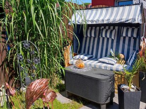 Ein Patio mit gestreiftem Sonnenschirm, einem Korbsessel und dekorativen Metallskulpturen.