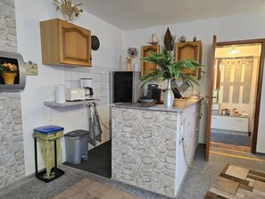 Eine kompakte Küche mit einer Steinservierplatte, Holzschränken, einer Mikrowelle und einer Kaffeemaschine.