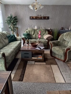 A living room with a sofa set, a coffee table, and a chandelier. - Dornbusch vacation apartment - quiet location on the outskirts - Dornbusch vacation apartment - in (Sassnitz auf Rügen)