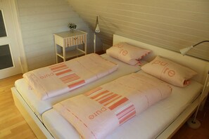 Un lit double avec une couverture à rayures, une table de chevet avec une lampe et une petite plante.