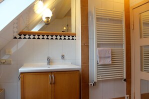 Une salle de bain équipée d’un lavabo, d’un miroir, d’un porte-serviettes et d’un radiateur.