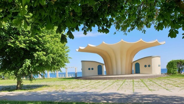 Un parque con una estructura arquitectónica singular, que presenta un espacio central abierto y dos edificios más pequeños.