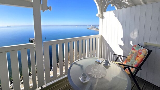 A balcony with a clear view of the sea, a table with a cup and saucer, and a chair. - Fürstenhof App. 405 - with balcony and sea view - Fürstennhof, App. 405 - 1. (Sassnitz auf Rügen)