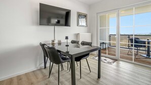 Une chambre moderne équipée d’une table à manger, de chaises, d’un téléviseur et d’une grande fenêtre donnant sur un beau paysage.