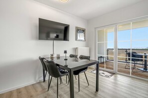 Ein modernes Zimmer mit Esstisch, Stühlen, einem Fernseher und einem großen Fenster mit Blick.