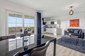 Eine moderne Wohnung mit Balkon, Essbereich, Wohnzimmer und Küche.