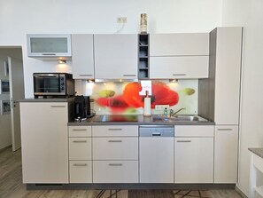 A modern kitchen with a microwave, coffee maker, and a dishwasher. - Fürstenhof, App. 304 - First row by the sea - Fürstenhof, App. 304 - Front row, (Sassnitz auf Rügen)