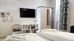 Camera d'albergo con due letti, televisione, armadio, una sedia e una libreria.