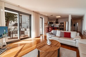 A modern living room with a sofa, a coffee table, and a dining area with chairs and a table. - Villa Friede-Marie, App. Freya - with wonderful sea view - Villa Friede-Marie, (Sassnitz auf Rügen)