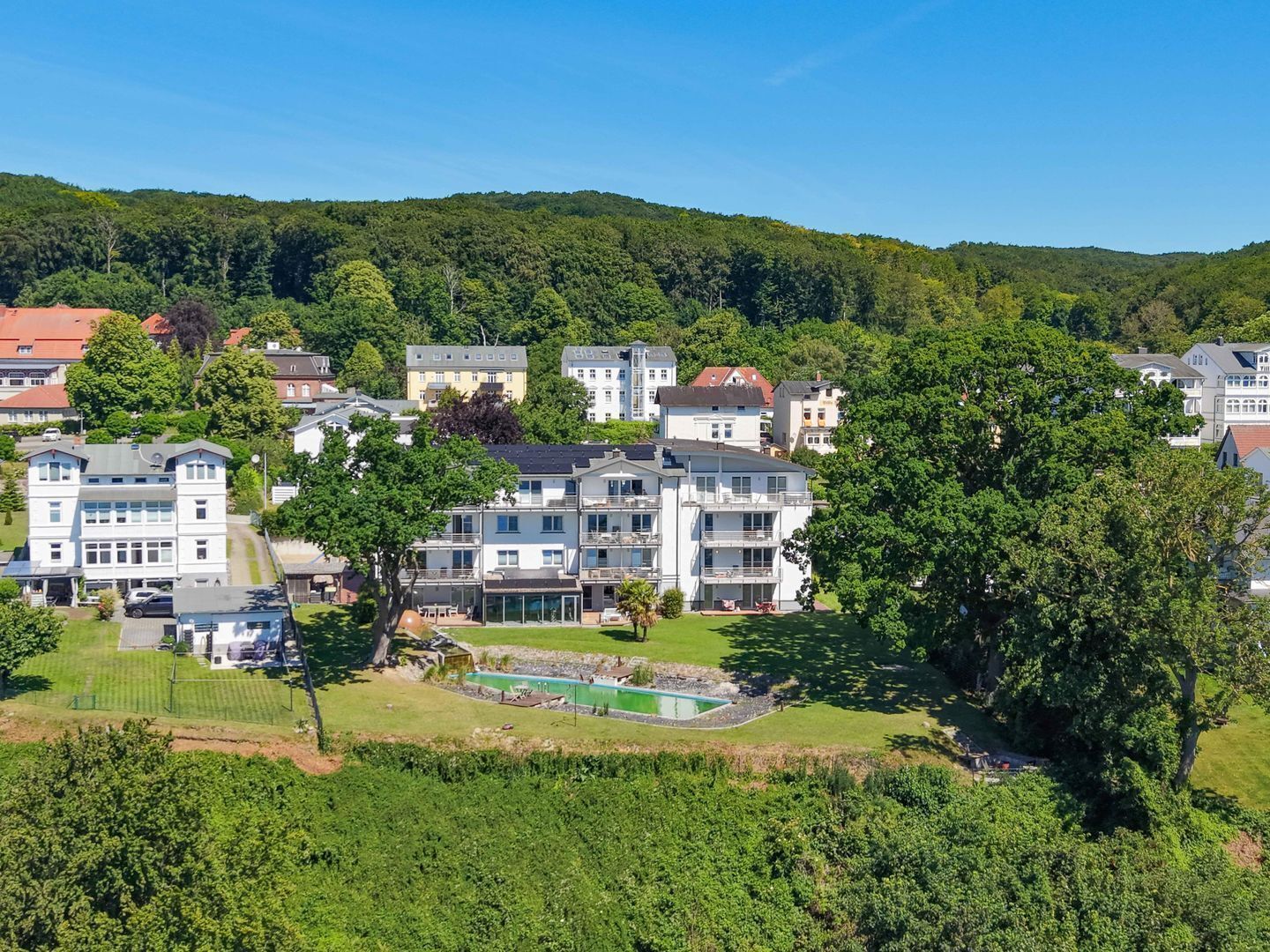 Zona residenziale con edifici a più piani, una piscina e un paesaggio verde e rigoglioso.