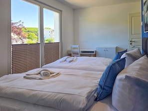 Ein Hotelzimmer mit zwei Betten, einem Schreibtisch und Blick ins Freie.