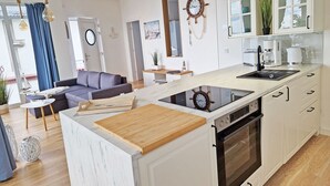 Cocina moderna con horno integrado, encimera de madera y decoración con timón de barco.