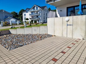 Ein Wohngebäude mit gepflasterter Terrasse und Kiesbeetanlage.