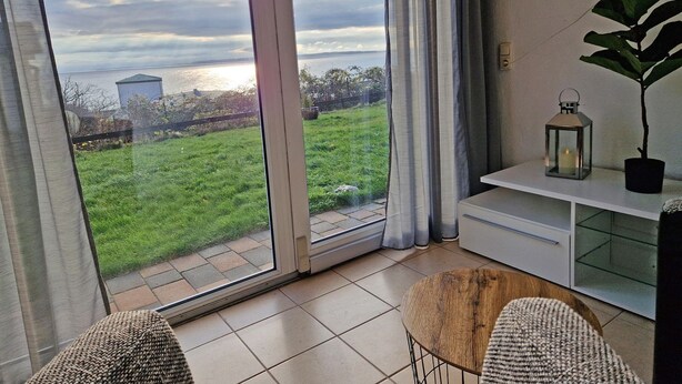 Ett rum med en skjutdörr av glas, ett litet träbord, ett vitt skåp och en krukväxt.