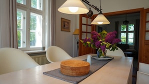 En matplats med ett bord, stolar, en vas med blommor och ett fönster med gardiner.