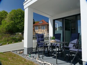 Eine Außenpatio mit Tisch, Stühlen, einem Blumentopf und Blick auf ein traditionelles Haus im Hintergrund.
