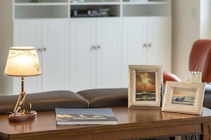 A wooden table with a lamp, two framed pictures, and a book. - Villa am Kreidebruch, FeWo OstseeWeitblick - panoramic view of the Baltic Sea (Sassnitz auf Rügen)