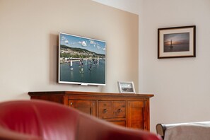 Un téléviseur fixé au mur affiche une scène côtière avec des bateaux.